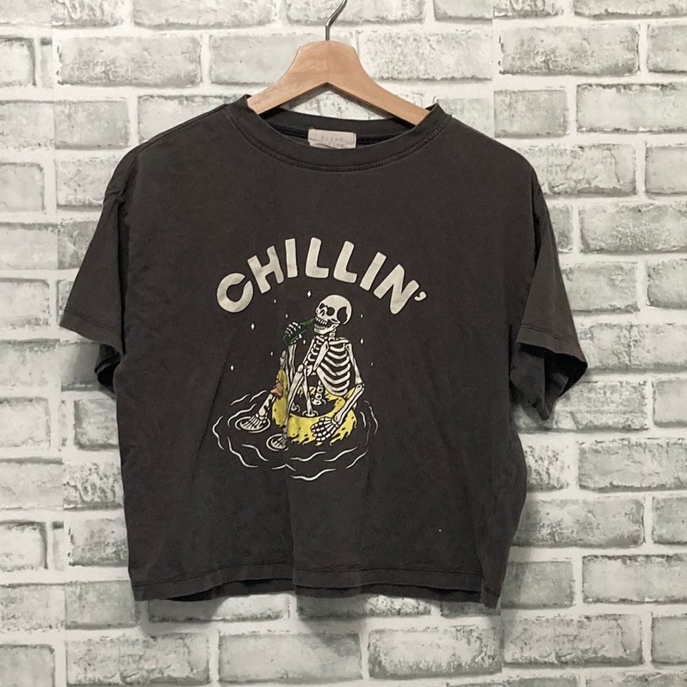 T-shirt with skeleton and duck floaty drinking sparkling water.